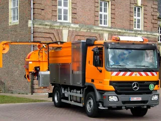Orangefarbenes HD-Spülfahrzeug von vorn, schwenkbarer Haspelausleger in Fahrstellung