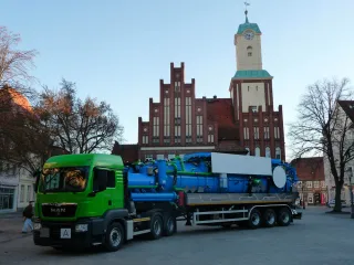 Saug-Sattelzug mit blauem Dreikammeraufbau vor einem historischen Rathaus