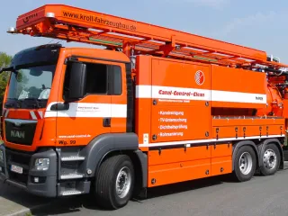 Orangefarbenes Saug-Spülfahrzeug mit Wasserrückgewinnung von vorn, Ausleger über dem Fahrerhaus